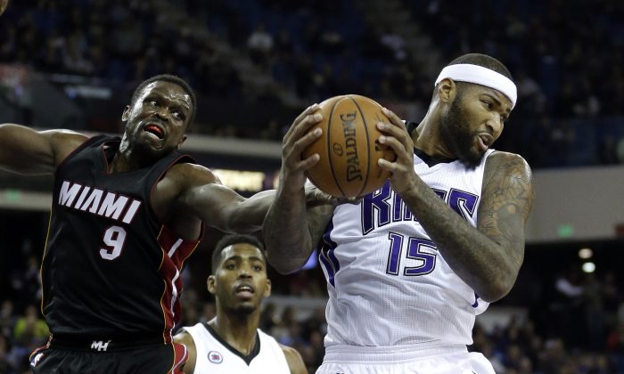 Sacramento Kings center DeMarcus Cousins,  right, pulls a rebound away from Miami Heat forward Luol Deng, left, of South Sudan, as Kings forward Jason Thompson looks on during the first quarter of an NBA basketball game in Sacramento, Calif., Friday, Jan. 16,  2015. (AP Photo/Rich Pedroncelli)