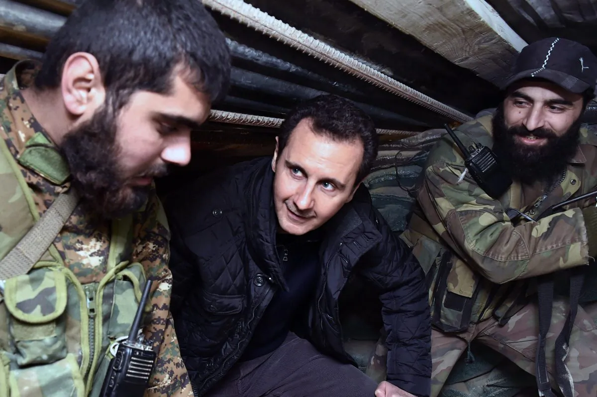 Syrian President Bashar Assad, center, speaks with Syrian troops during his visit to the front line in the eastern Damascus district of Jobar, Syria, on Dec. 31, 2014. (AP Photo/SANA)