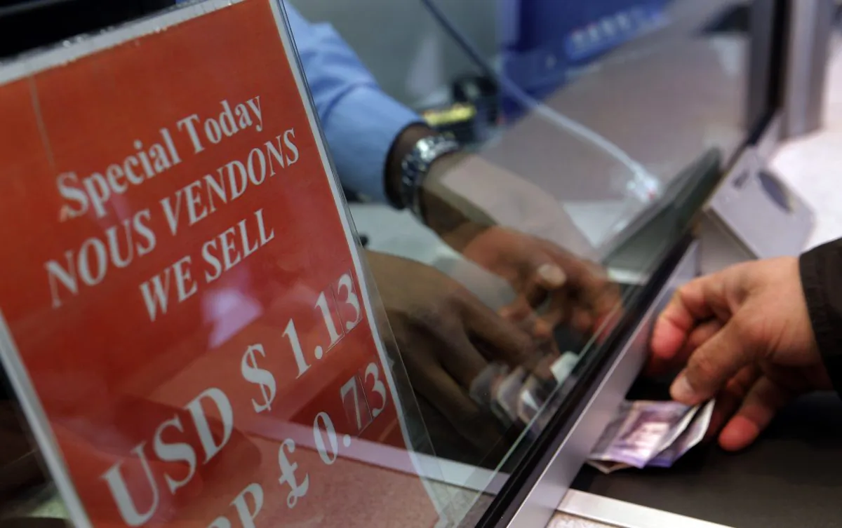 A man exchanges money at a currency exchange office on the Champs Elysees in Paris on Jan. 6, 2015. Long a symbol of American economic might, the rising dollar is denting the earnings of US companies that operate overseas. (AP Photo/Christophe Ena)