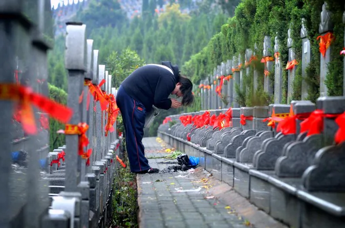 A person prays in front of a gravestone as people across China pay their respects to friends and relatives two days before Tomb-Sweeping Day (ChinaFotoPress/Getty Images)
