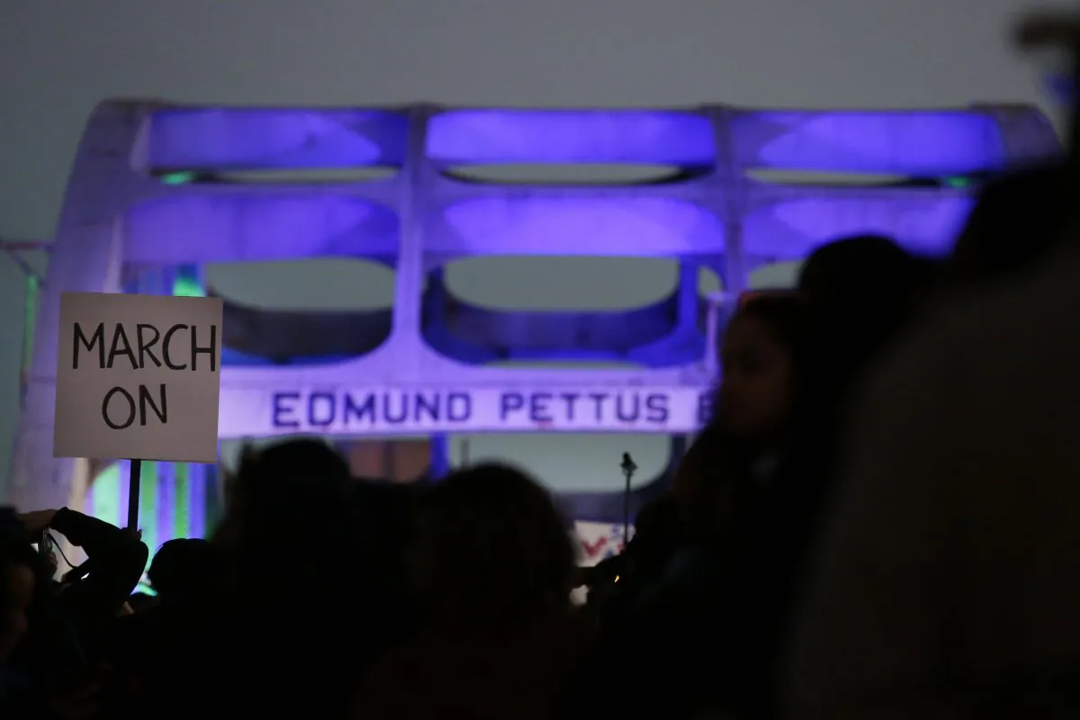 Marchers hold up a "March On" sign as they make their way towards the Edmund Pettus Bridge the Edmund Pettus Bridge in honor of Martin Luther King Jr., in Selma, Ala., on Jan. 18, 2015. (Brynn Anderson/AP Photo)