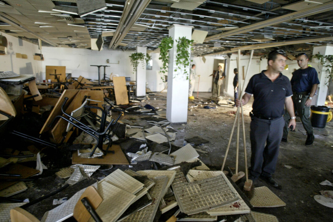 In this July 31, 2002, file photo, workers clean the inside of a cafeteria hours after a bomb exploded at Hebrew University in Jerusalem, killing nine, four of them Americans, and wounding more than 70. Terrorism victims are suing the Palestinian Liberation Organization and the Palestinian Authority in New York for damages under the Anti-Terrorism Act, which allows victims of terrorism to seek compensation through the U.S. Federal Court System. (AP Photo/David Guttenfelder, File)