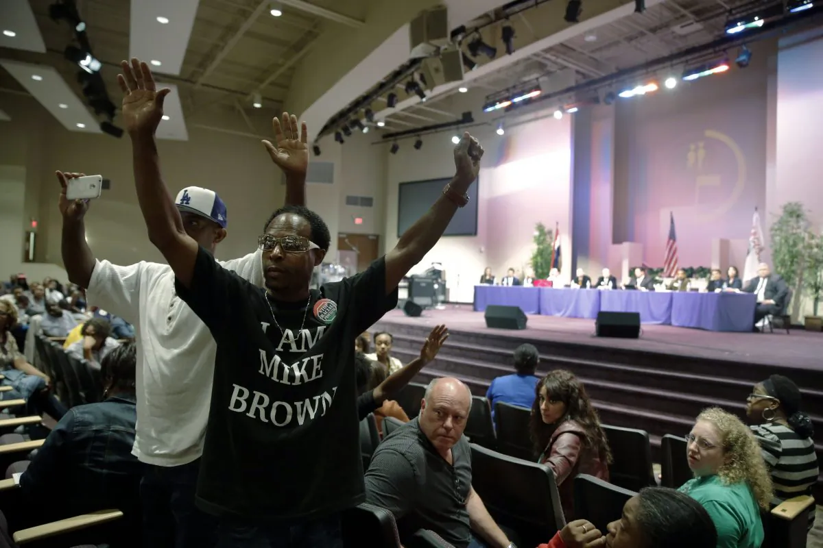 FILE - In this Sept. 9, 2014 file photo,  Marurice Brown raises his arms during a public comments portion of a meeting of the Ferguson City Council, back right, in Ferguson, Mo.  A lawsuit filed Wednesday seeks protection from a state statute that requires a name and address on political flyers. (AP Photo/Jeff Roberson, File)