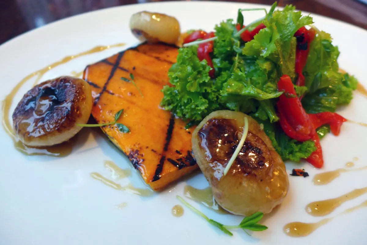 Grilled Bourbon-Maple-Glazed Butternut Squash with Roasted Cipollini Onions and Mustard Greens. (Courtesy of Rock Center Café)