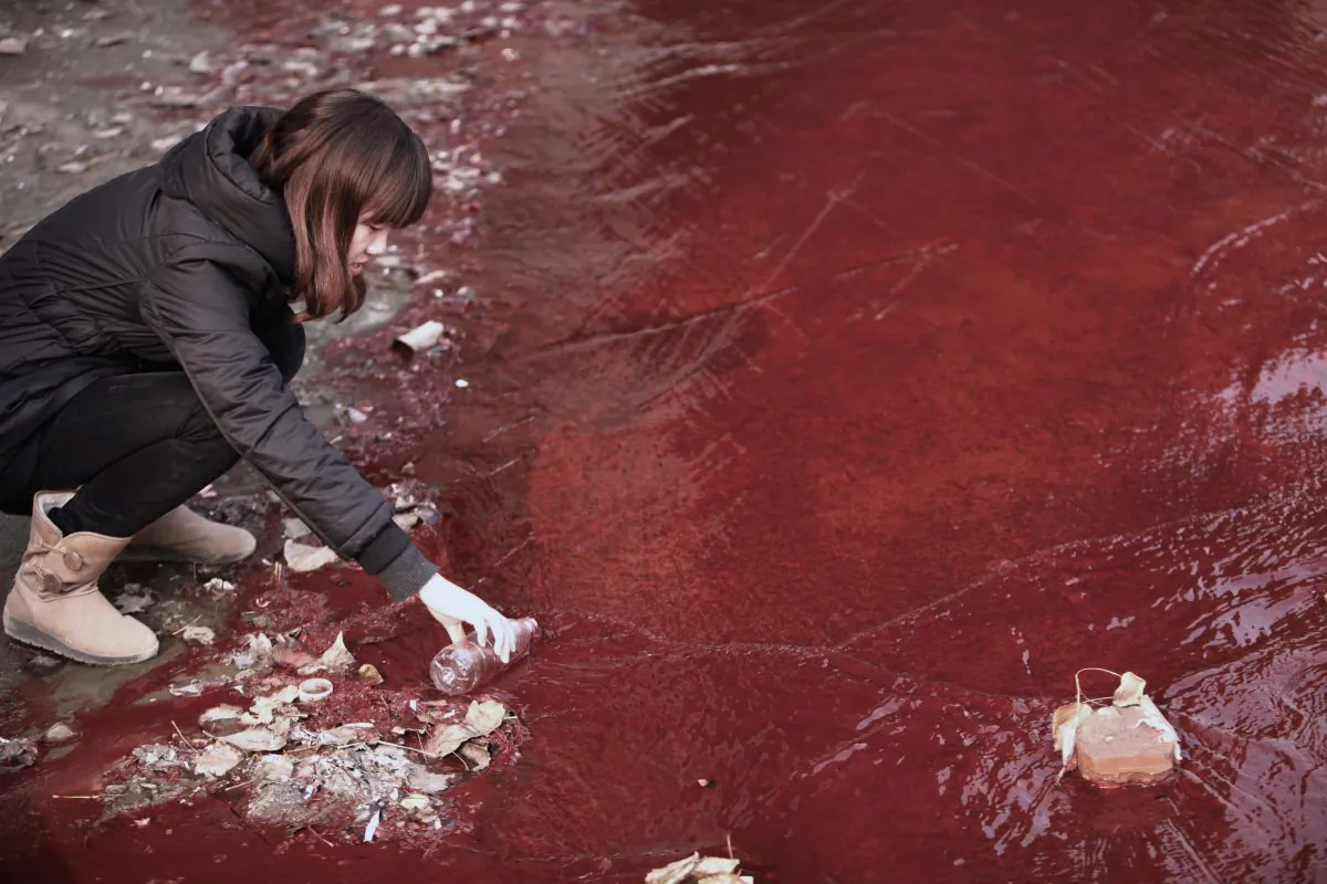 A woman collects a sample of the red polluted water flowing from a sewer into the Jian River in Luoyang, in central China's Henan Province, on Dec. 13, 2011. Pollution from a medicine factory in Daliuying Village in Henan Province creates a sour smell in the air, and makes underground water salty and unclear, state news media recently reported. (STR/AFP/Getty Images)