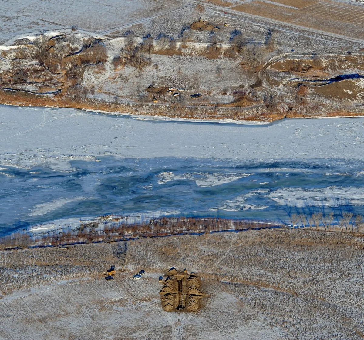 Crews work to contain an oil spill from Bridger Pipeline's broken pipeline near Glendive, Mont., in this aerial view showing both sides of the river on Monday, Jan. 19, 2015. Officials said that they were bringing truckloads of drinking water to Glendive after traces of 50,000 gallons of oil that spilled into the Yellowstone River were found in the city's water supply. (AP Photo/The Billings Gazette, Larry Mayer)
