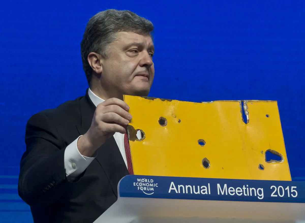 Ukrainian President Petro Poroshenko shows a piece of a bus that was attacked recently during the panel "The Future of Ukraine" in Davos, Switzerland, Wednesday, Jan. 21, 2015. The meeting runs Jan. 21 through 24 under the overarching theme "The New Global Context". (AP Photo/Michel Euler)