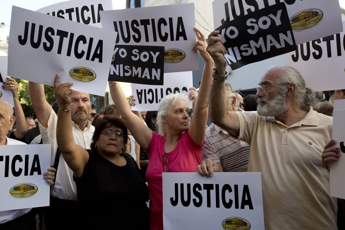 People gather outside the AMIA Jewish community center asking for "Justice" in the death of a prosecutor who had accused Argentina’s president of a criminal conspiracy, in Buenos Aires, Argentina, Wednesday, Jan. 21, 2015. Special prosecutor Alberto Nisman, who had been investigating the 1994 bombing of the Jewish community center that killed 85 people and who accused President Cristina Fernandez of shielding Iranian suspects, was found dead from a gunshot to the head, in his apartment late Sunday, hours before he was to testify in a Congressional hearing about the case. (AP Photo/Rodrigo Abd)