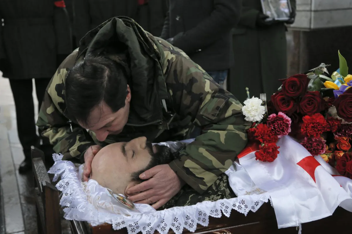 A man pays his final respect to the body of serviceman Thomas Sukhiashvili, a Georgian national who was killed in fighting against Russia-backed separatists, during a commemoration ceremony in Kiev, Ukraine, on Wednesday, Jan. 21, 2015. Sukhiashvil was a veteran of NATO-led campaigns in Afghanistan and Iraq and Georgia’s 2008 war with Russia. A former senior Georgian military official says around 100 Georgian volunteers are fighting alongside Ukrainian forces in the conflict against Russian-backed separatists. (AP Photo/Efrem Lukatsky)