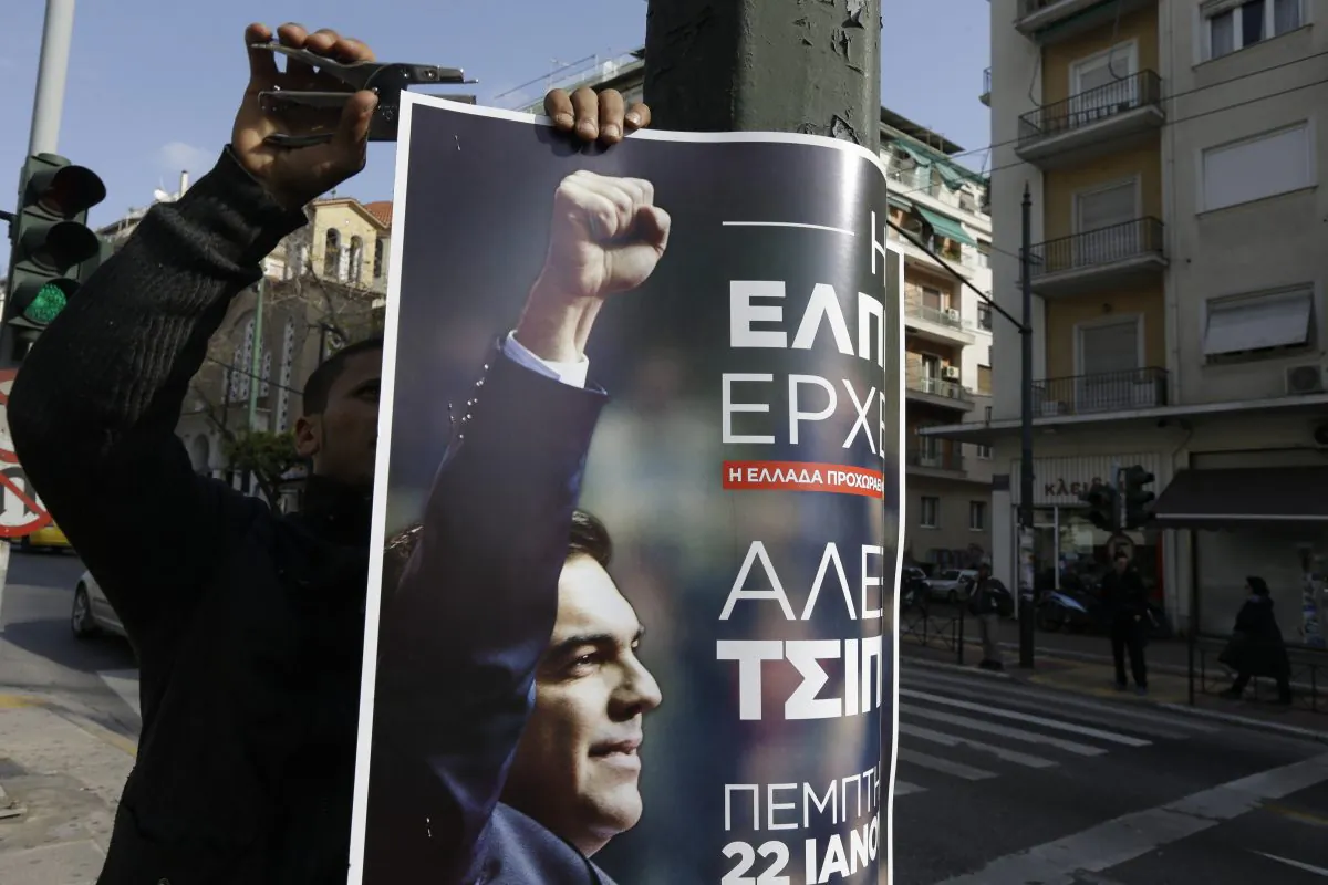 An Egyptian worker displays a poster on an electricity pole promoting Alexis Tsipras, head of Greece's Syriza left-wing main opposition party, pre-election speech in Athens on Jan. 21, 2015. His left-wing Syriza party is poised to win a general election in Greece Sunday, a landmark event for Europe’s ambitious political newcomers with domestic resonance in a country with a long history of deadly political division that has recently been ravaged by financial crisis. (AP Photo/Thanassis Stavrakis)