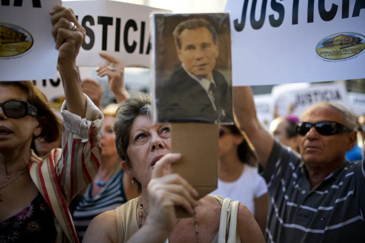 A woman chants the Argentine national anthem holding a portrait of the late prosecutor Alberto Nisman outside the AMIA Jewish community center in Buenos Aires, Argentina, Wednesday, Jan. 21, 2015. Nisman, who had been investigating the 1994 bombing of the Jewish community center that killed 85 people and who accused President Cristina Fernandez of shielding Iranian suspects, was found dead from a gunshot to the head, in his apartment late Sunday, hours before he was to testify in a Congressional hearing about the case. (AP Photo/Rodrigo Abd)