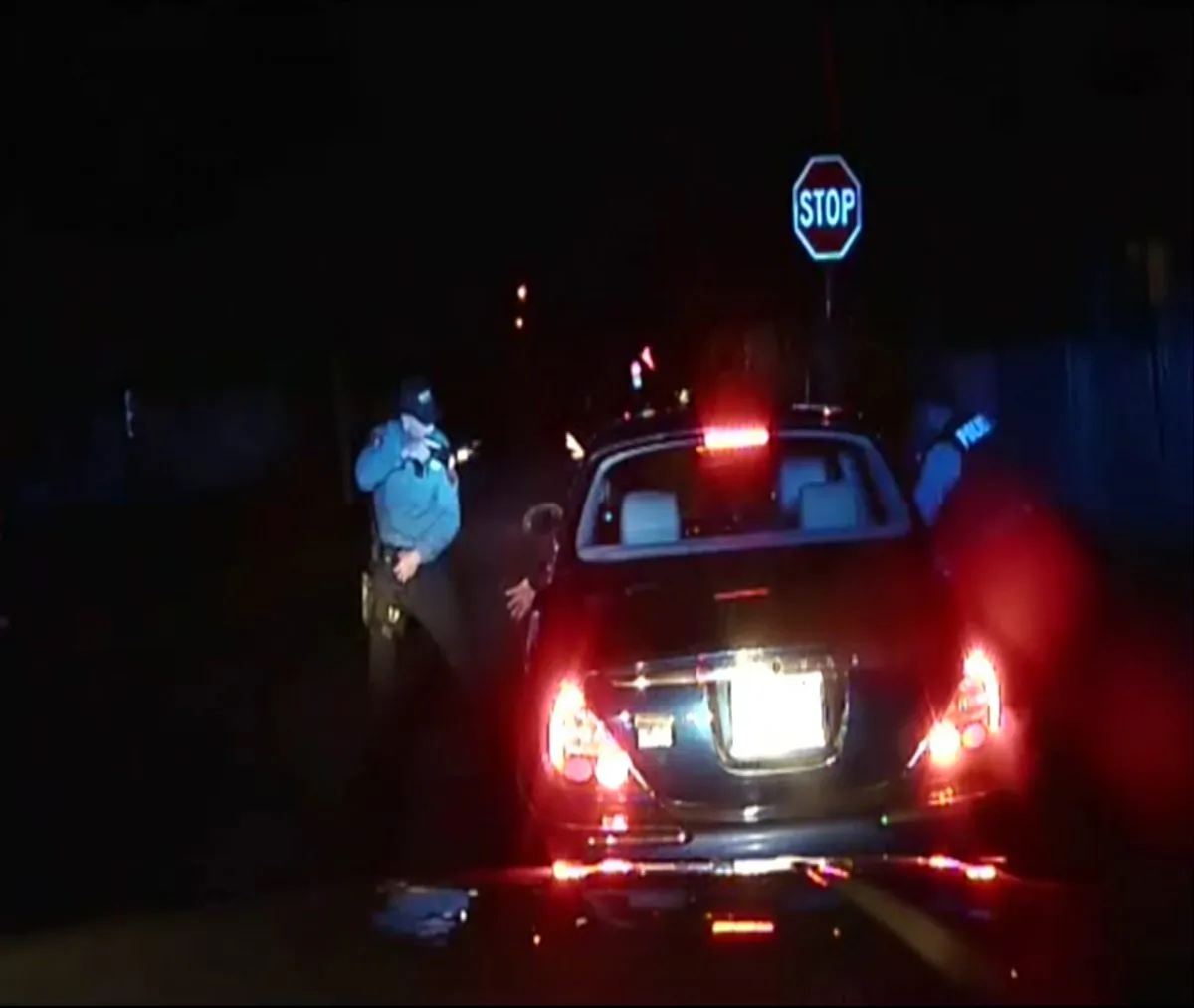 In this frame grab from an officer's dashboard camera taken Dec. 30, 2014, and provided by the Bridgeton, N.J. Police Department, police officers Braheme Days and Roger Worley stand near a car they pulled over for running a stop sign in Bridgeton. One of the officers warned his partner that he could see a gun in the glove compartment. The nearly two-minute standoff resulted in the death of Jerame Reid, one of two men in the car. (AP Photo/Bridgeton Police Department)