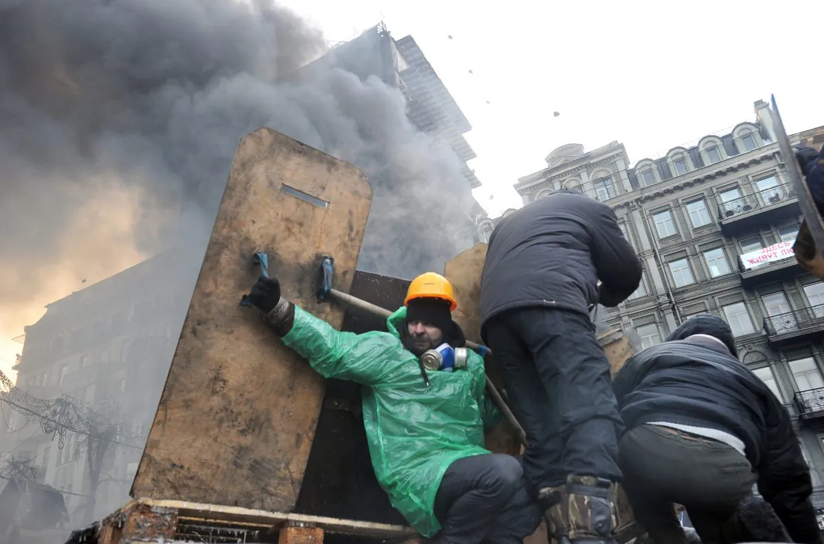Anti-government protesters take cover under makeshift shields during clash with riot police in Kyiv on Jan. 25, 2014. (Genya Savilov/AFP/Getty Images)