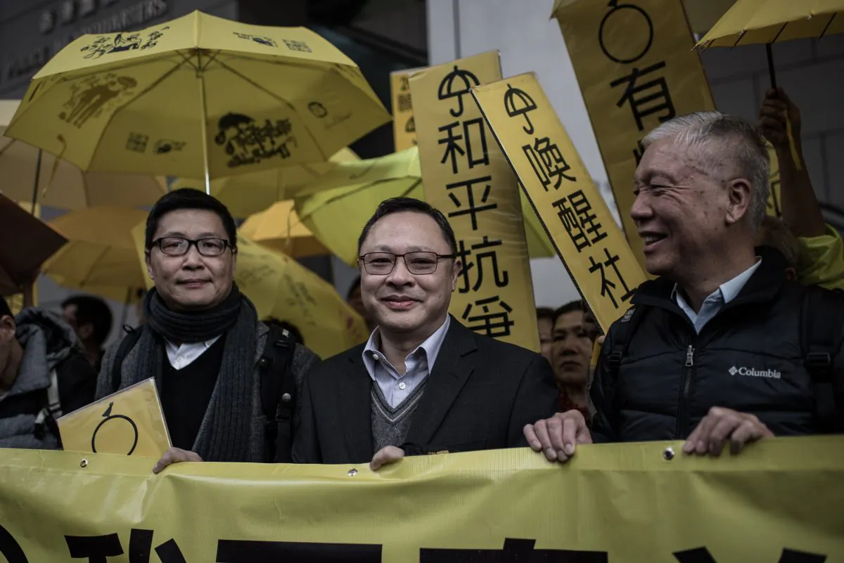 Leading pro-democracy activists, Chan Kin-man (L), Benny Tai Yiu-ting (C) and Chu Yiu-ming hold a banner in front of the Wanchai police station in Hong Kong on Jan. 24, 2015. (Philippe Lopez/AFP/Getty Images)