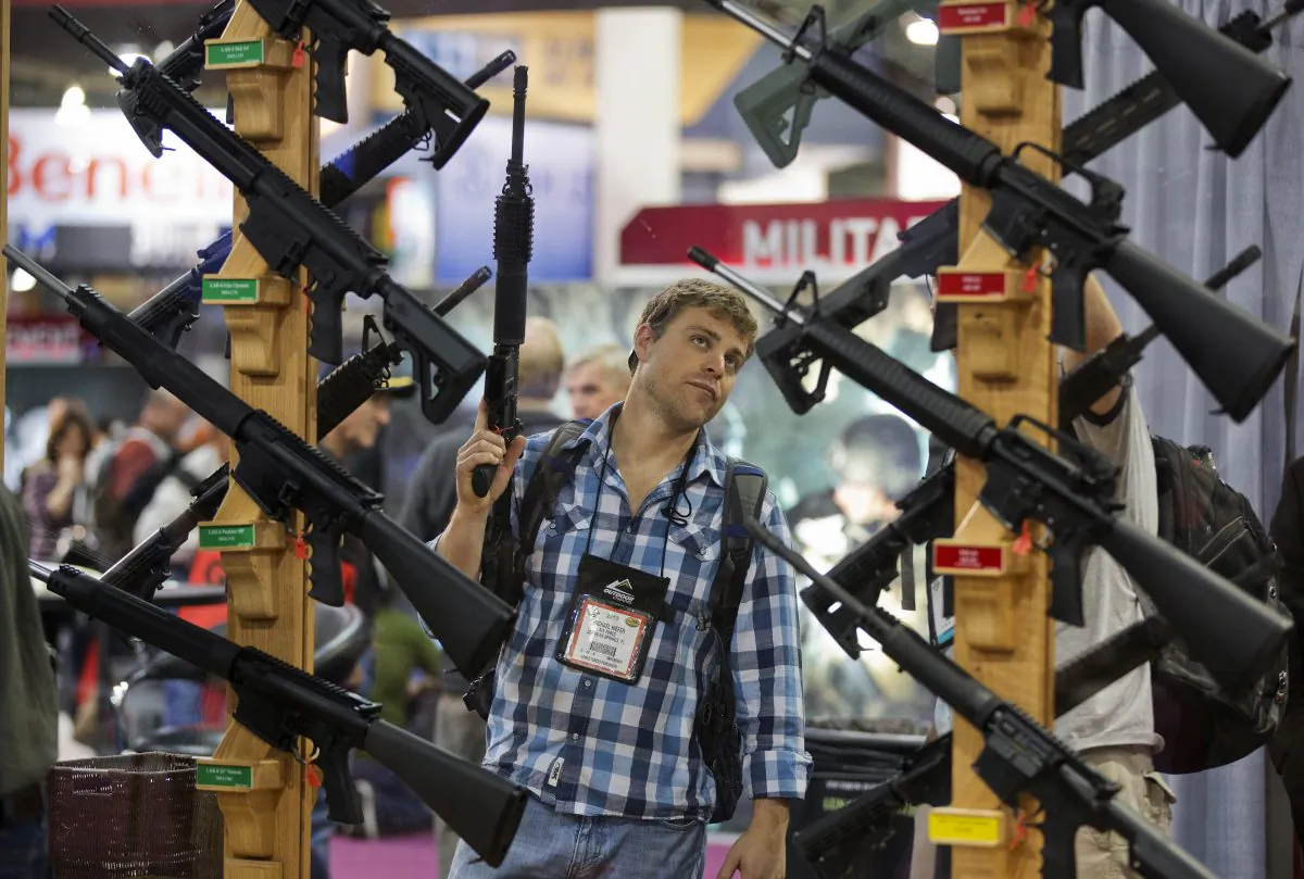A man looks at a display of rifles at the Rock River Arms booth during the 35th annual SHOT Show in Las Vegas on Jan. 17, 2013. (AP Photo/Julie Jacobson)