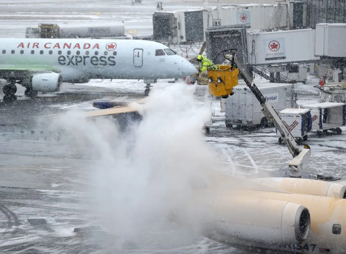 A plane is de-iced during a light snow at LaGuardia Airport in New York on Jan. 26, 2015. Airlines canceled thousands of flights into and out of East Coast airports as a major snowstorm packing up to three feet of snow barrels down on the region. (AP Photo/Seth Wenig)