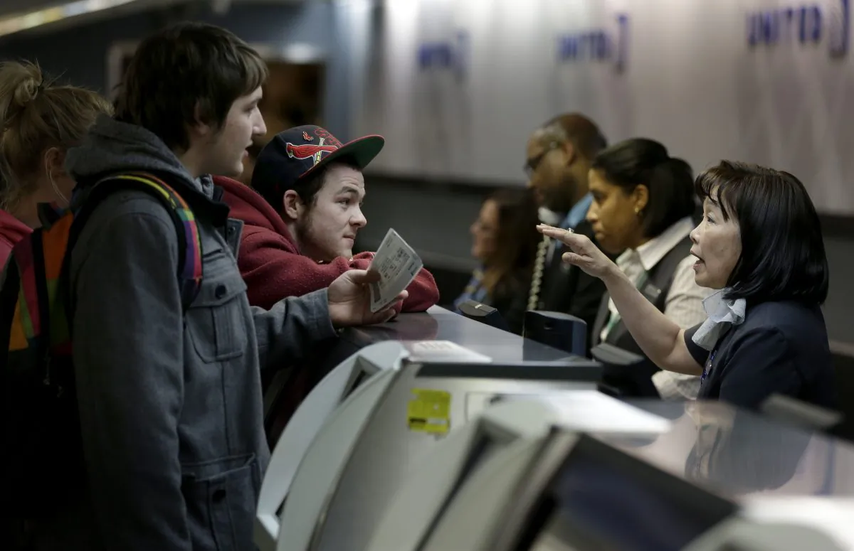 Brandon Bybee, left, and Cory McKenrick, second from left, talk with a ticket agent to try and move up their flight to Illinois in order to beat an expected snow storm at LaGuardia Airport in New York, Monday, Jan. 26, 2015. Airlines canceled thousands of flights into and out of East Coast airports as a major snowstorm packing up to 3 feet of snow barrels down on the region. (AP Photo/Seth Wenig)
