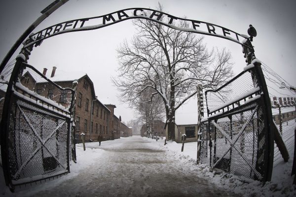A woman walks in the snow near the entrance to the former Nazi concentration camp Auschwitz-Birkenau with the inscription 
