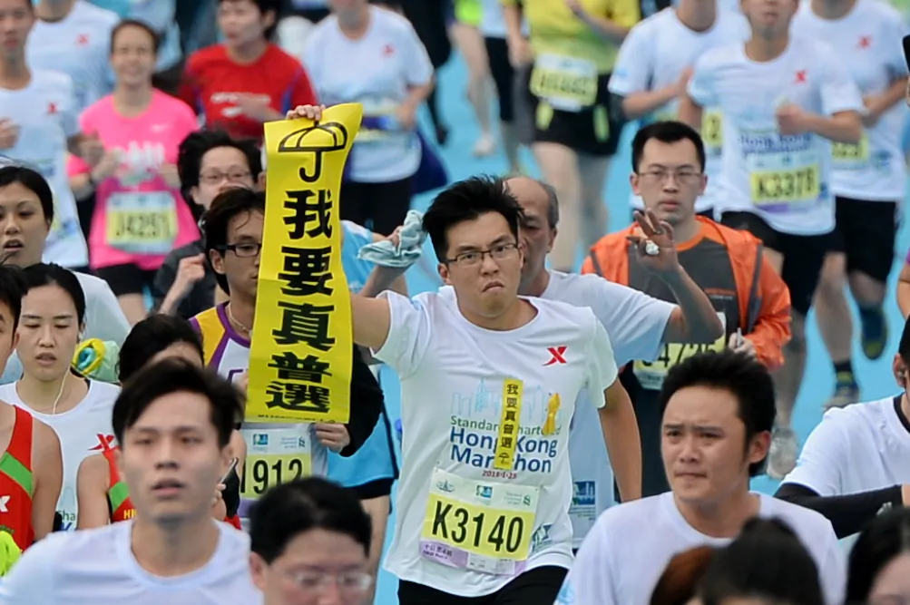 A marathon runner holds up a Lion Rock "I want genuine universal suffrage banner" during the 2015 Hong Kong Marathon on Jan. 25, 2015. (Sung Cheung-loong/Epoch Times)