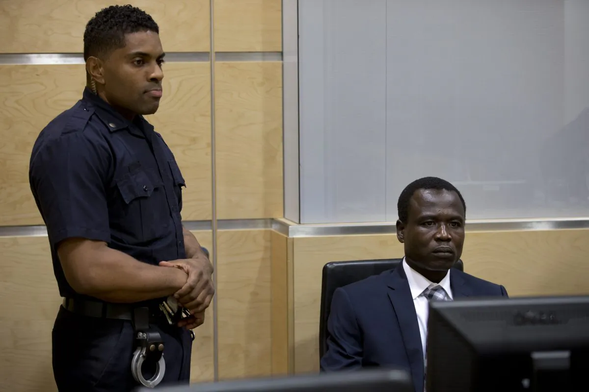 Dominic Ongwen, right, a Ugandan commander in warlord Joseph Kony's feared militia, waits for the start of court procedures as he made his first appearance at the International Criminal Court in The Hague, Netherlands, Monday, Jan. 26, 2015. Ongwen arrived in The Hague last week after being taken into custody in Central African Republic. He faces war crimes and crimes against humanity charges for his alleged role in a reign of terror that has spanned more than 25 years in central Africa's Great Lakes region. (AP Photo/Peter Dejong, Pool)