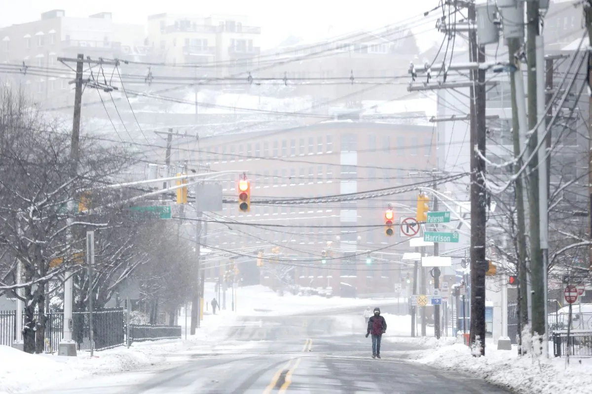 A pedestrian walks on a snow covered road after an overnight snowstorm, Tuesday, Jan. 27, 2015, in Hoboken, N.J. (AP Photo/Julio Cortez)