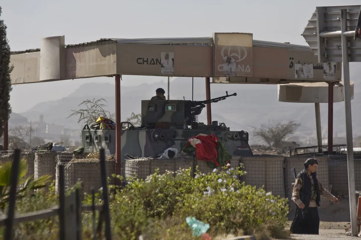 A Houthi Shiite Yemeni, background, mans a machine gun atop an armored personnel carrier, seized from the presidential guards during clashes, outside the presidential palace in Sanaa, Yemen, Thursday, Jan. 22, 2015. (AP Photo/Hani Mohammed)