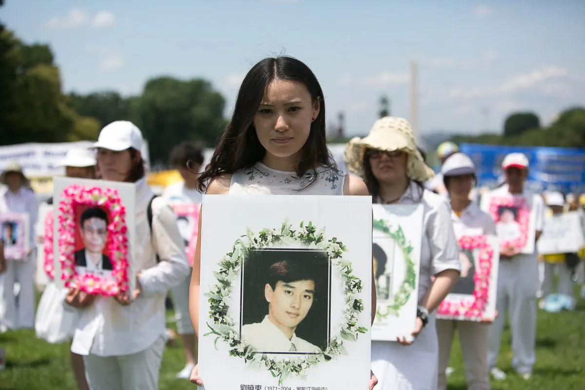 A young woman holds a poster during a rally in Washington on July 17, 2014, of Chinese man who was tortured to death for practicing Falun Gong inside China. (Edward Dai/Epoch Times)