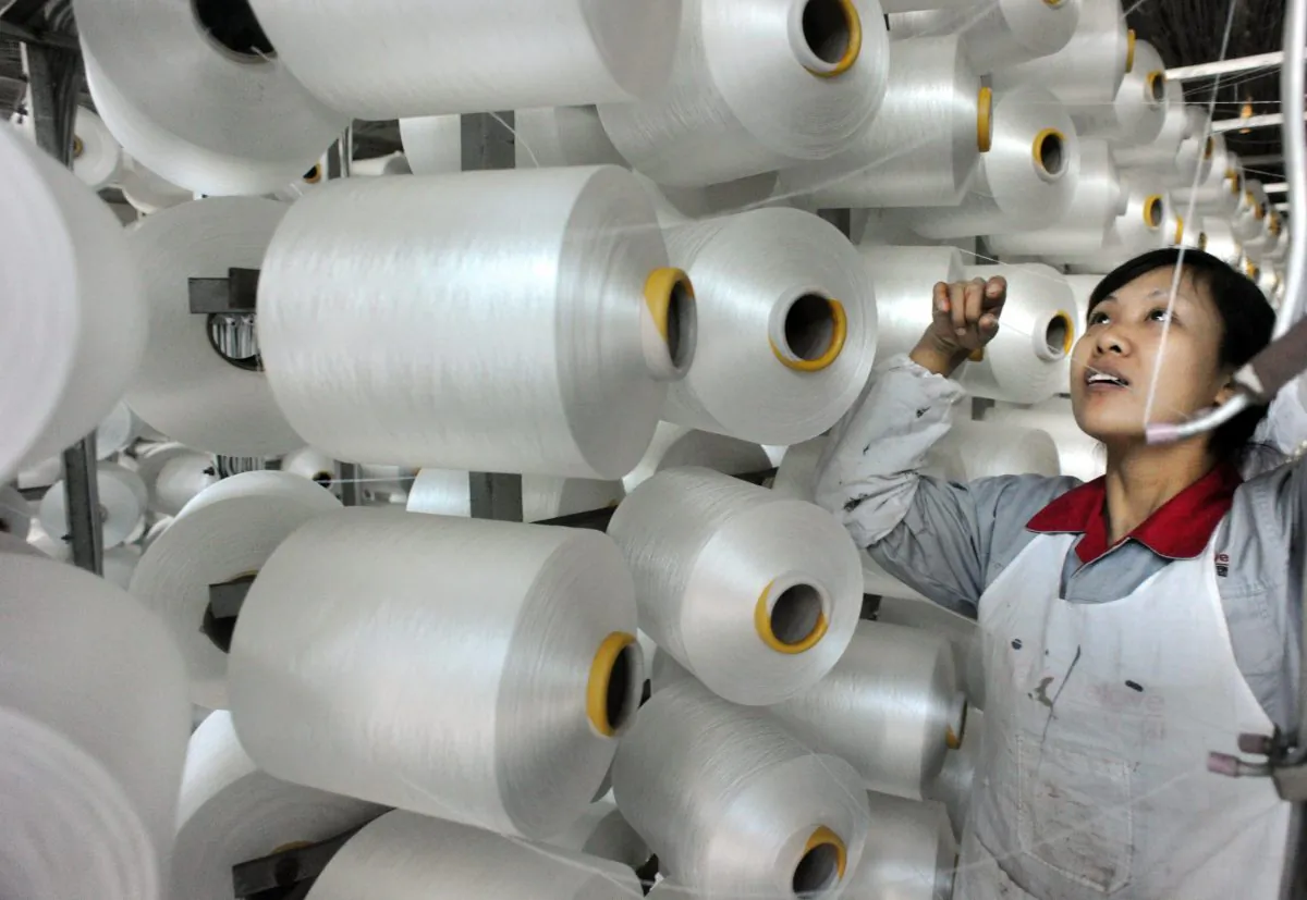 A Chinese worker checks a machine making blankets for export at a factory in Yiwu, Zhejiang province, on Jan. 12. (STR/AFP/Getty Images)