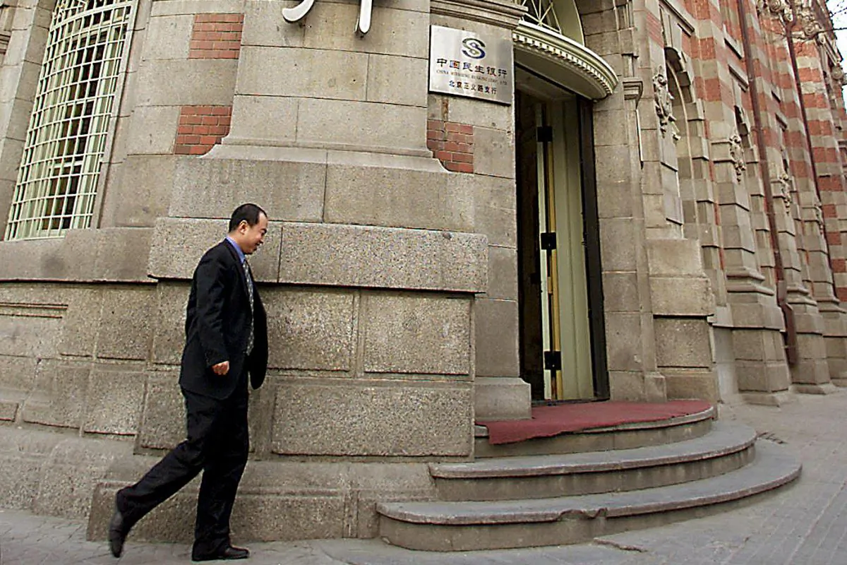 In this file photo, a man walks by the head office of China's largest private lender Minsheng Bank in Beijing, on Feb. 25, 2002. On Jan. 31, mainland Chinese media reported that Mao Xiaofeng, the president of the bank, had been detained in a corruption investigation. (AFP/Getty Images)
