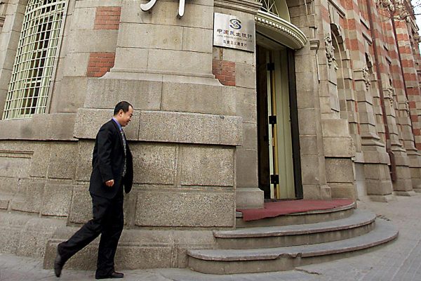 In this file photo, a man walks by the head office of China's largest private lender Minsheng Bank in Beijing, on Feb. 25, 2002. On Jan. 31, mainland Chinese media reported that the Mao Xiaofeng, the president of the bank, had been detained in a corruption investigation. (AFP/Getty Images)