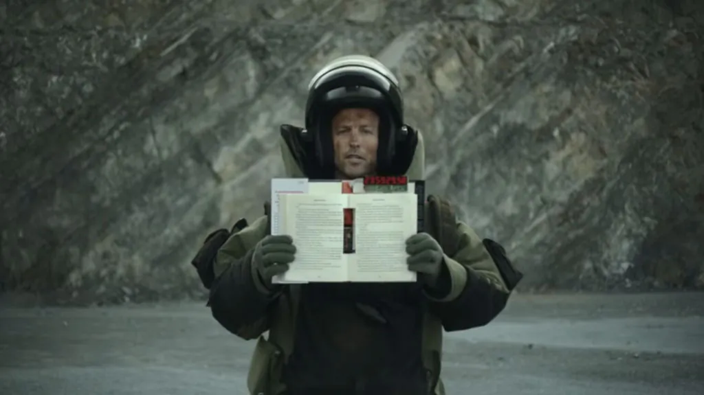 An actor holds up a self-detonating version of “Private Vegas” by James Patterson in this screenshot from James Patterson's YouTube channel. (Epoch Times)