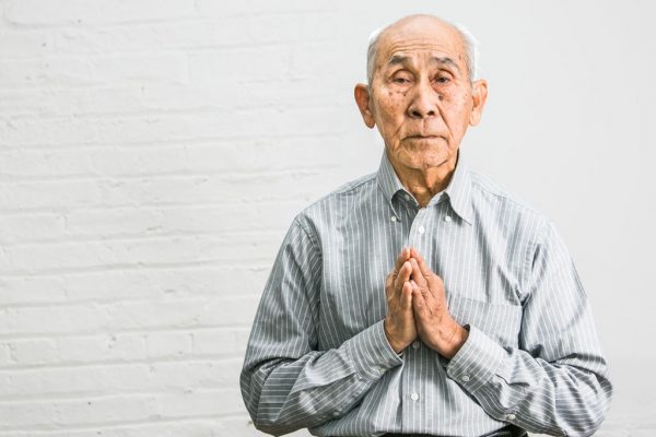 Khmer Rouge survivor Nal Oum performs "Sampeah," the Cambodian greeting or a way of showing respect, in New York, on Jan. 23, 2015. (Benjamin Chasteen/Epoch Times)