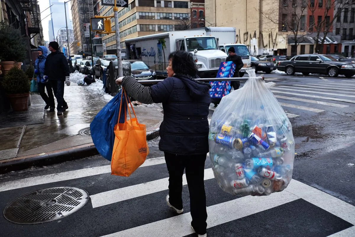 A woman balances a load of recyclable cans and bottles she collected from trash cans to sell in Manhattan on Jan. 30, 2015. New claims for U.S. unemployment insurance benefits plunged to the lowest level in nearly 15 years, the Labor Department reported. (Jewel Samad/AFP/Getty Images)