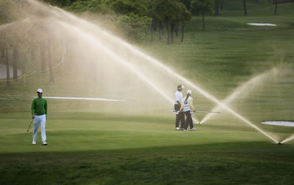 Adam Blyth (L) and Clay Deverslook look on as the sprinkler goes off on the 9th green before the group finishes play during the round one of the BMW Asian Open 2006 at Tomson Golf Club in Shanghai, China. (Cancan Chu/Getty Images) 