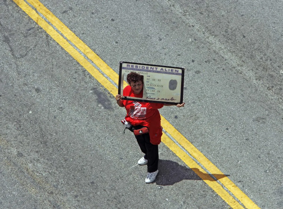 A protester holding a banner that looks like a United States green card walks down Broadway Street in the downtown Los Angeles Tuesday, May 1, 2007. (AP Photo/Kevork Djansezian)
