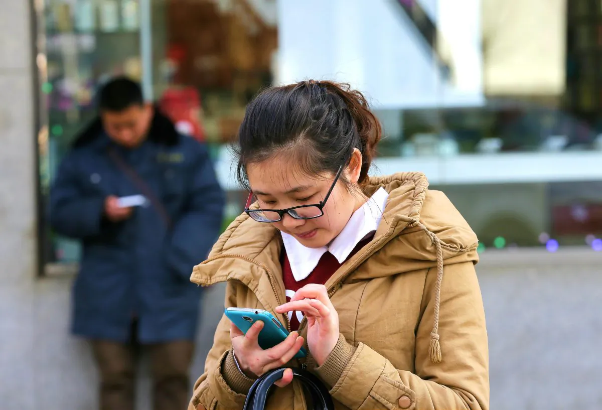Chinese people check on their smartphones on a street in Beijing Monday, Feb. 16, 2015. (AP Photo/Andy Wong)