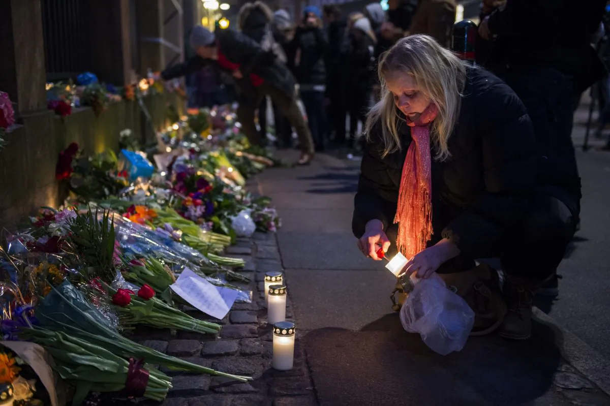 A woman lights a candle to honor the shooting victims outside the main Synagogue in Copenhagen, Denmark on February 15, 2015. (Odd Andersen/AFP/Getty Images) 