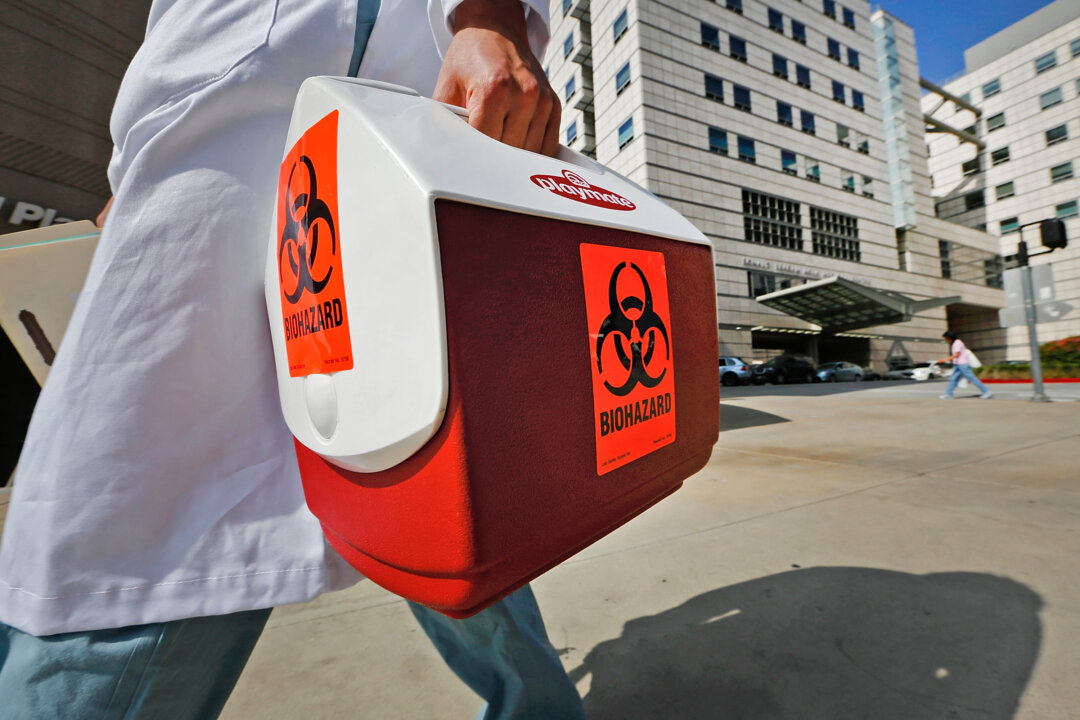 A research assistant with the David Geffen School of Medicine at UCLA carries a portable cooler marked with a biohazard label past the Ronald Reagan UCLA Medical Center in Los Angeles, Feb. 19, 2015. (Damian Dovarganes/AP Photo)