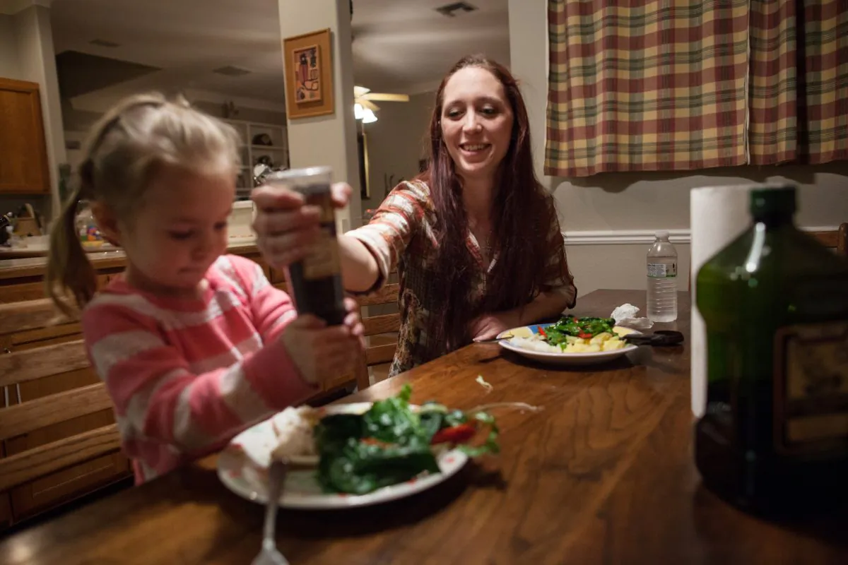 Maggie Barcellano, receiver of food stamps benefits, helps her daughter, Zoe, 3, use a pepper grinder with dinner at Barcellano's father's house in Austin, Texas on Saturday, Jan. 25, 2014. (AP Photo/Tamir Kalifa)
