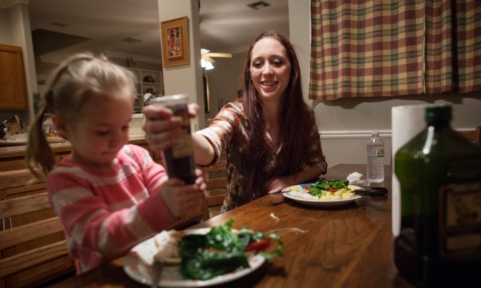 Maggie Barcellano, receiver of food stamps benefits, helps her daughter, Zoe, 3, use a pepper grinder with dinner at Barcellano's father's house in Austin, Texas on Saturday, Jan. 25, 2014. (AP Photo/Tamir Kalifa)