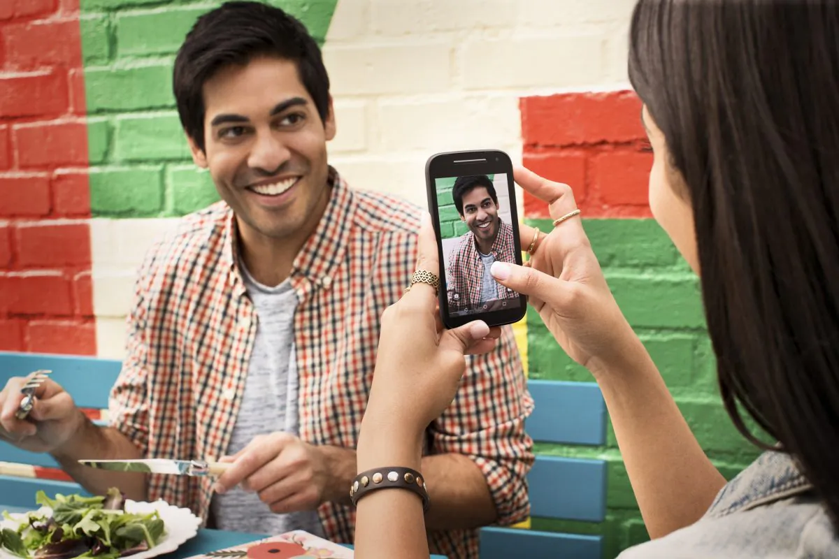A woman takes a photo of a man with the new Moto E. The second generation phone was released Feb. 25, 2015 world-wide. (Courtesy of Motorola)