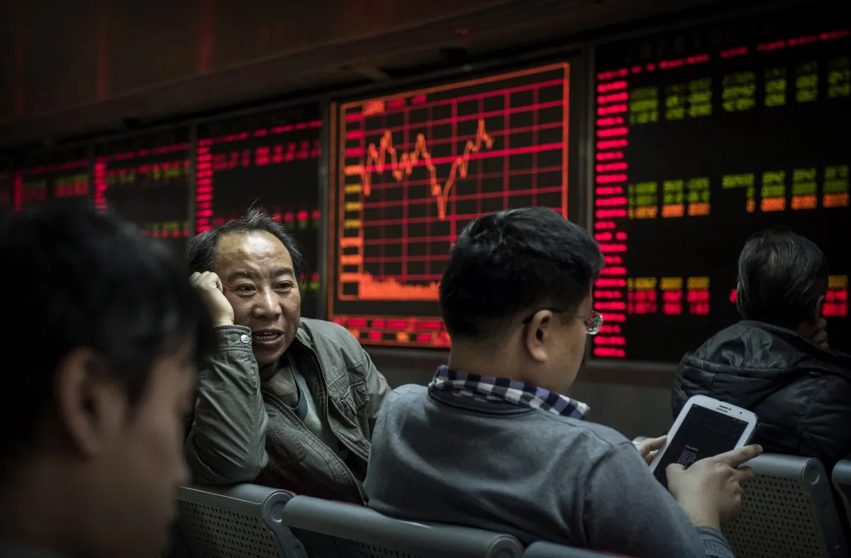 Chinese day traders chat in front of stock tickers on a board at a brokerage firm in Beijing, on Jan 22, 2015. (Kevin Frayer/Getty Images)