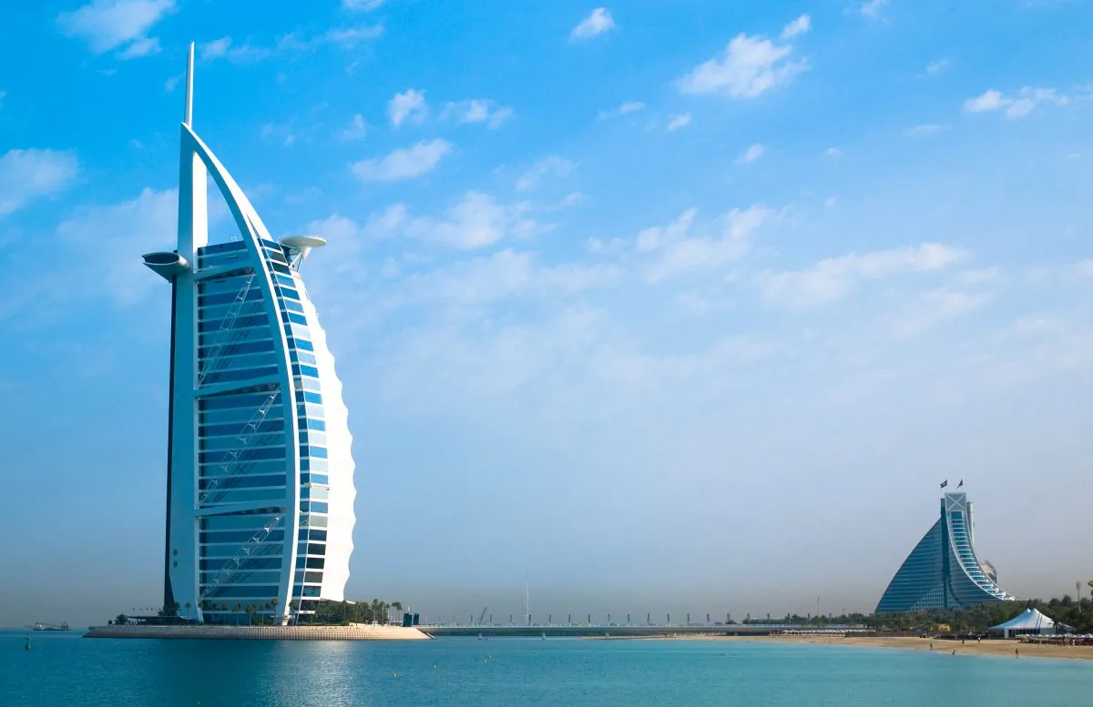 Burj Al Arab, the world’s only 7-star hotel, stands on an artificial island off Jumeirah Beach and is connected to the mainland by a private bridge. Its shape is designed to mimic the sail of a ship. The building on the right is the Jumeirah Beach Hotel. These are just two unique buildings in a city renowned for its unique buildings. (Joi Ito/Wikipedia)