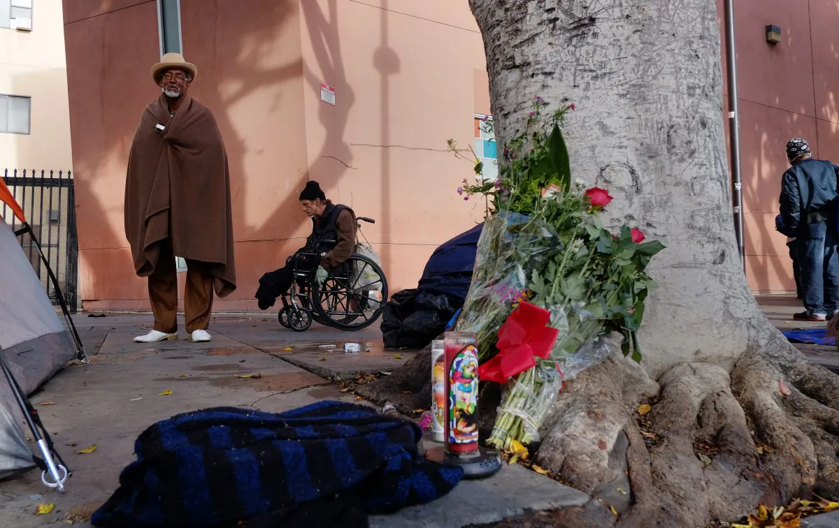 Ceola Waddell, 58, left, a homeless man who says he witnessed the police shooting on Skid Row on Sunday, stands by a makeshift memorial for the victim in downtown Los Angeles on Monday, March 2, 2015. (AP Photo/Richard Vogel)