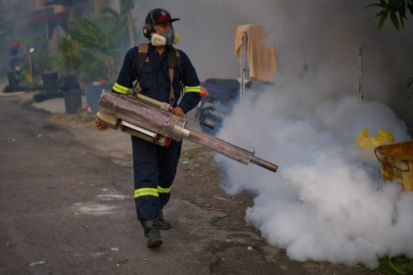 A municipal council worker dispenses insecticide using a fogging machine during a dengue-prevention spraying in Ampang, in the suburbs of Kuala Lumpur on Feb. 11, 2014. Dengue fever is spread by mosquitoes and causes joint pain, nausea, high fevers, and rashes; and in severe cases, it results in death. (Mohd Rasfan/AFP/Getty Images)