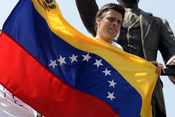 Leopoldo Lopez, an ardent opponent of Venezuela's socialist government facing an arrest warrant after President Nicolas Maduro ordered his arrest on charges of homicide and inciting violence, stands at the monument of Cuba's most important independence-era hero, Jose Marti, as he demonstrates with a national flag in Caracas before turning himself in to authorities, on February 18, 2014. Fugitive Venezuelan opposition leader Lopez, blamed by Maduro for violent clashes that left three people dead last week, appeared at an anti-government rally in eastern Caracas and quickly surrendered to the National Guard after delivering a brief speech. AFP PHOTO / LEO RAMIREZ (Photo credit should read