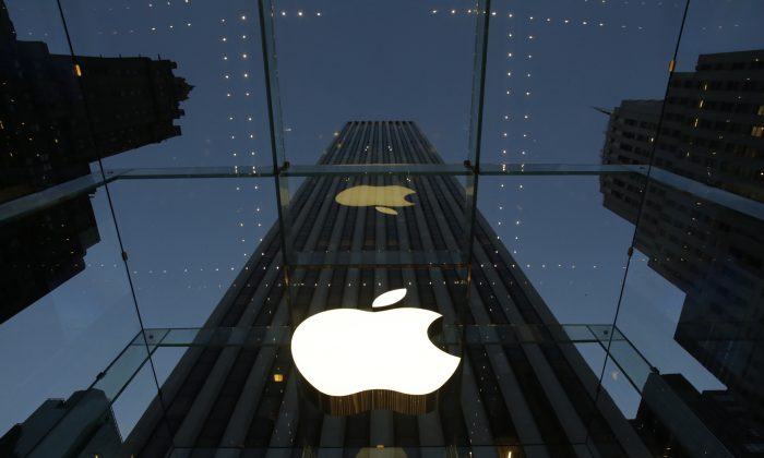 In this Wednesday, Nov. 20, 2013, file photo, the Apple logo is illuminated in the entrance to the Fifth Avenue Apple store, in New York. (AP Photo/Mark Lennihan)