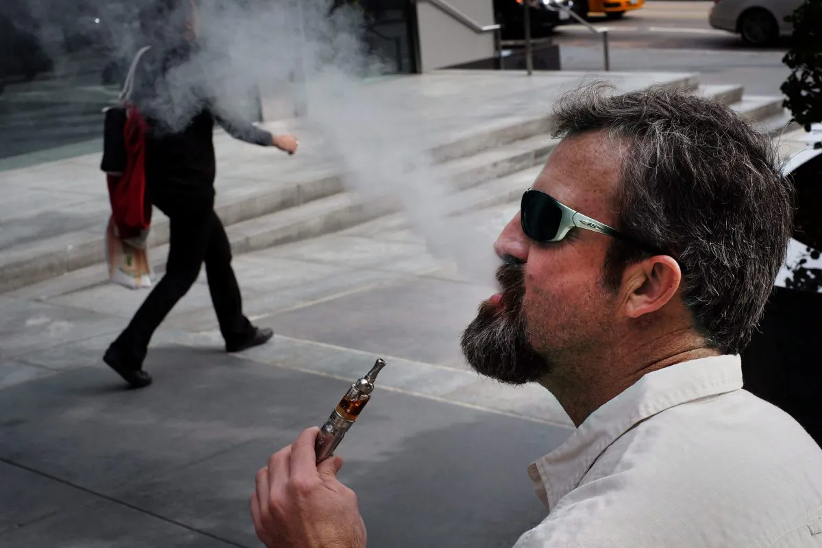A man smokes an electronic cigarette in the street. (AP Photo/Richard Vogel)