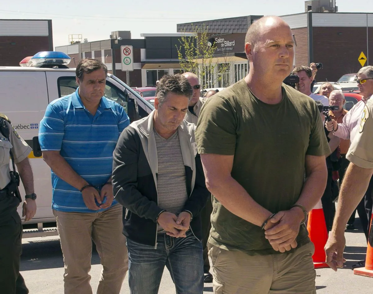 Former Montreal Maine and Atlantic Railway Ltd. employees Tom Harding (R), Jean Demaitre (C) and Richard Labrie are escorted by police to appear in court in Lac-Megantic on May 13, 2014. Harding is now back in court to have a date set for a preliminary hearing—something his lawyer says prosecutors are seeking to prevent. (The Canadian Press/Ryan Remiorz)
