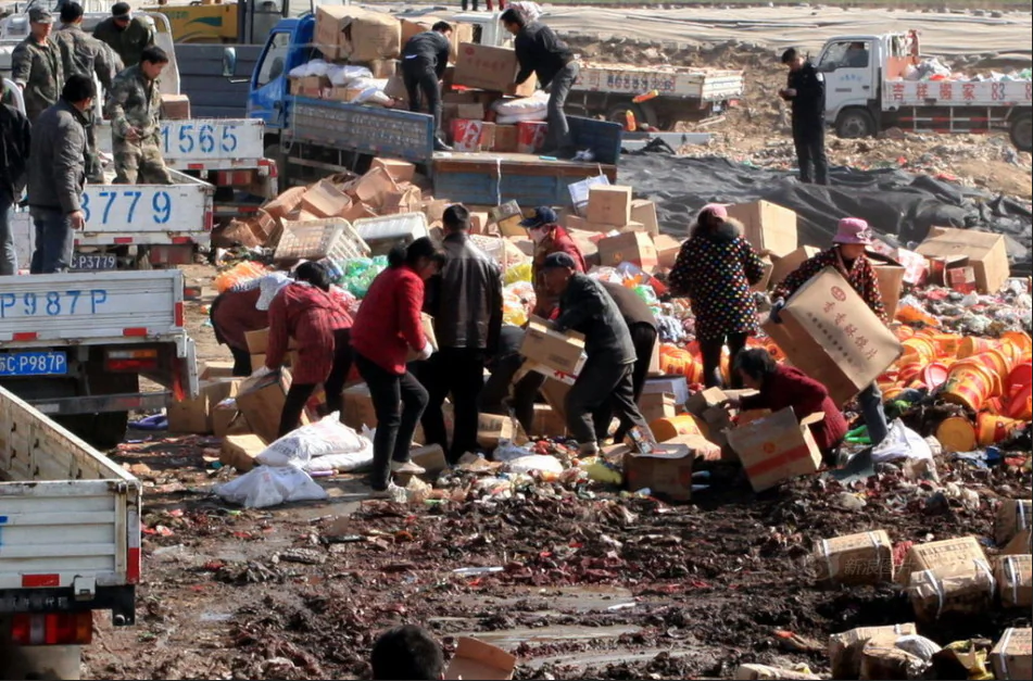 A photograph on Sina News, a Chinese website, shows people in the city of Xuzhou, Jiangsu Province, scrambling to salvage the boxes of substandard and counterfeit foodstuffs being destroyed and discarded by local authorities on March 11. Some came back for several helpings. (Screenshot/Epoch Times)